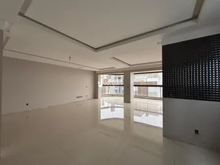 Interior de uma sala ampla com piso claro e paredes brancas.