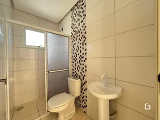 Foto de um banheiro com revestimento de azulejos brancos e detalhes em padrão.