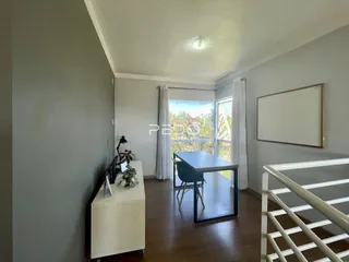 Ambiente interno com piso de madeira e grande janela de vista para o exterior.