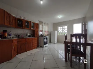 Interior de uma cozinha com armários de madeira e piso cerâmico.