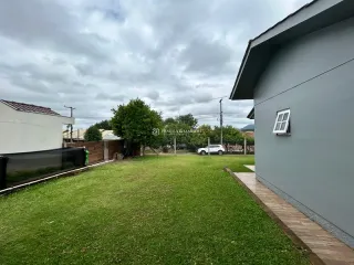 Fachada externa de uma residência com gramado verde e deck de madeira.