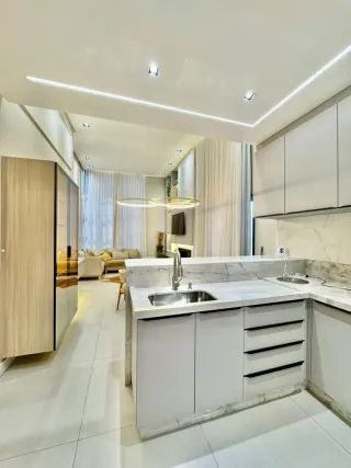 Cozinha moderna com armários brancos e bancadas claras.