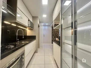 Interior de cozinha moderna com armários brancos e bancadas escuras.
