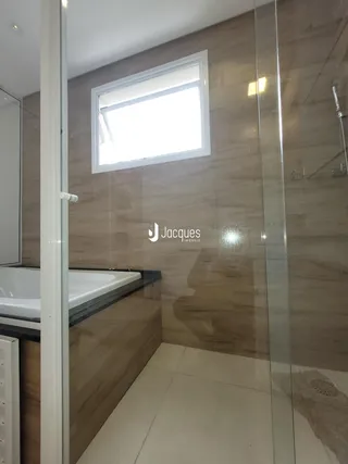 Foto de um banheiro com banheira e box de vidro em um imóvel.