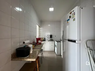 Uma cozinha com paredes brancas e piso claro.