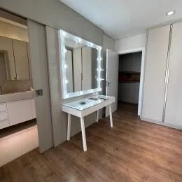 Sala de estar com espelho e piso de madeira clara.