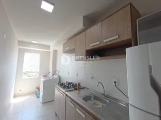 Vista da cozinha com armários de madeira e piso claro em um imóvel no Brasil.