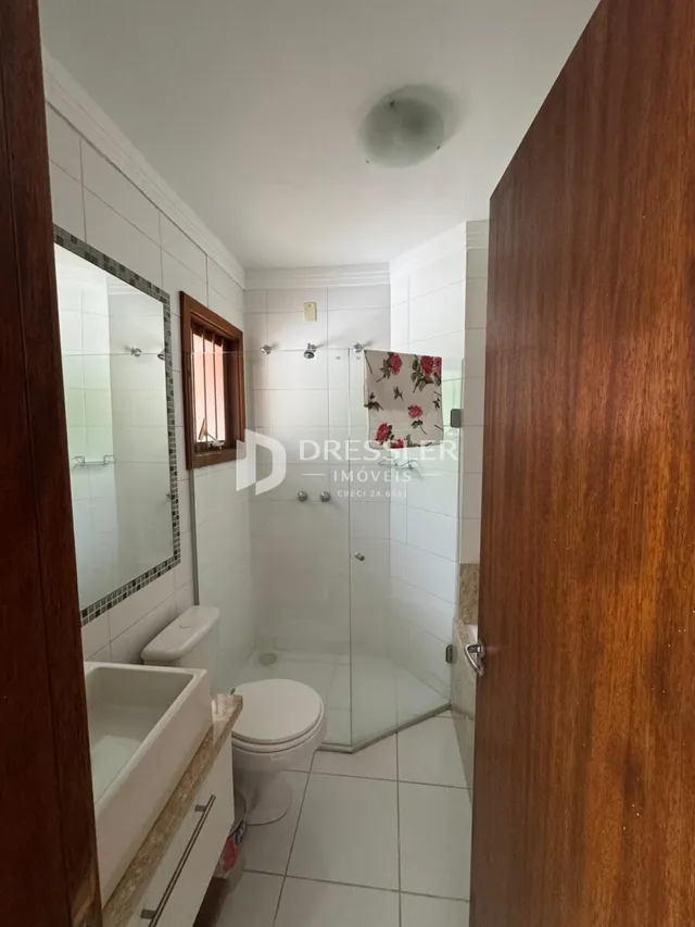 Foto de um banheiro com box de vidro e revestimento cerâmico.