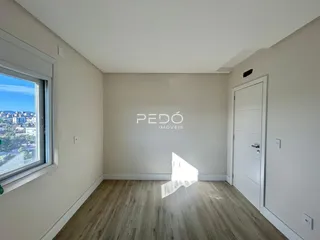 Sala de estar com piso de madeira clara e vista da paisagem urbana.