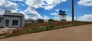 Vista externa de uma propriedade com terreno inclinado e vegetação.