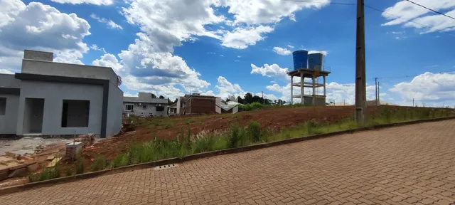Vista externa de uma propriedade com terreno inclinado e vegetação.