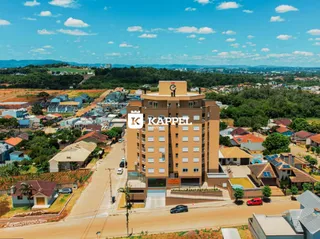 Vista externa de um grande edifício residencial em Lajeado, Brasil, com paisagem ao fundo.