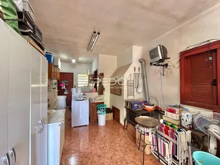 Interior de uma cozinha com piso de cerâmica e armários brancos.