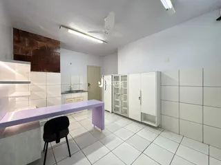 Interior de uma cozinha moderna com armários brancos e piso de cerâmica clara.