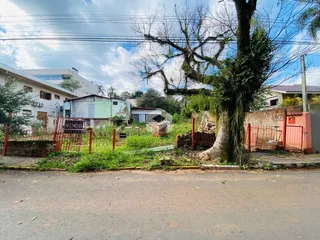 Vista da fachada de uma propriedade com cerca e vegetação ao lado da rua.