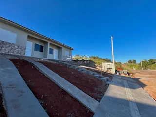 Vista externa de uma casa em construção com terra e concreto no terreno.