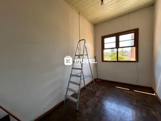 Foto de um cômodo interno com paredes brancas e piso de madeira.