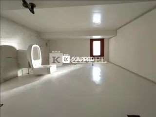 Foto de um ambiente interno vazio com paredes brancas e piso claro.