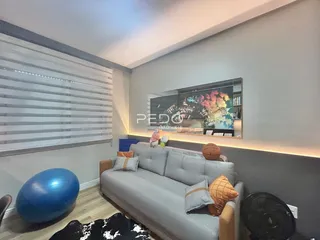 Sala de estar com sofá cinza e televisão na parede.