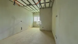Interior de um espaço com paredes brancas e teto de estrutura exposta.