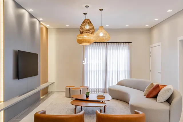 Sala de estar moderna e bem iluminada com sofá e mesas de centro.
