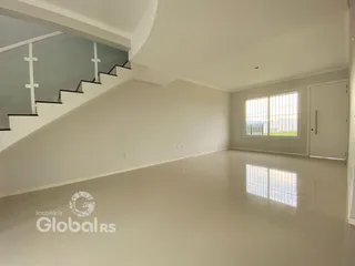 Ambiente interno de uma sala ampla com escada e grande janela.