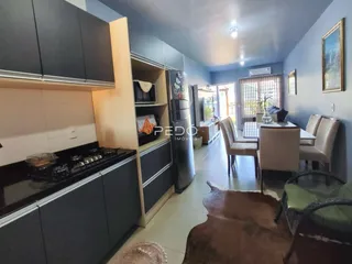 Imagem de uma sala de estar com cozinha e área de jantar em um imóvel no Brasil.