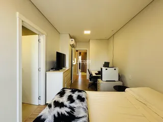 Quarto interno com cama e porta de acesso a um corredor.