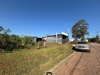 Vista externa de uma propriedade com vegetação e um edifício ao fundo.