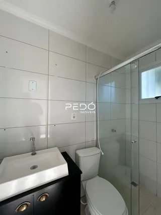 Foto de um banheiro com revestimento cerâmico e box de vidro transparente.