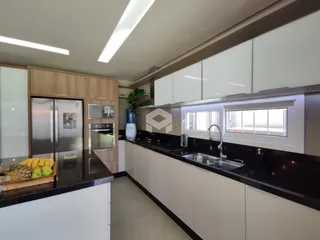 Cozinha moderna com armários brancos e bancadas escuras.