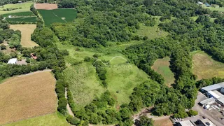 Vista aérea de uma área rural com vegetação densa e campos verdes.