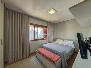 Quarto com vista para a cidade e cortinas claras.