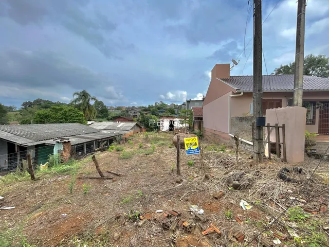 Vista externa de uma propriedade com terreno baldio e edificações ao fundo.