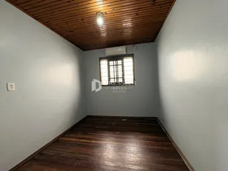 Quarto com piso de madeira e teto inclinado em imóvel no Brasil.