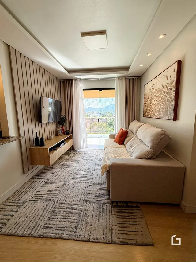 Sala de estar com piso de madeira e tapete no interior de uma residência.