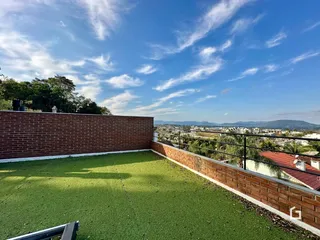 Vista de um terraço com muro de tijolos e gramado verde.