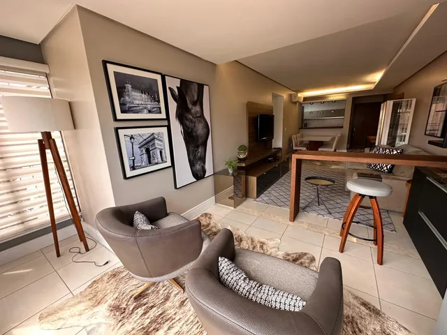 Sala de estar com duas poltronas e piso de mármore claro.