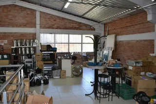 Interior de um espaço com paredes de tijolo aparente e teto metálico.