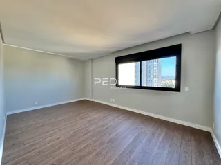 Ambiente interno de uma sala com piso de madeira e janela com vista.
