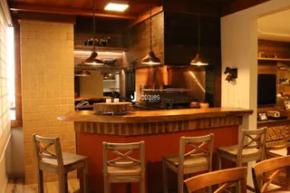 Vista interna de uma cozinha com bancada de madeira e detalhes em tijolo.