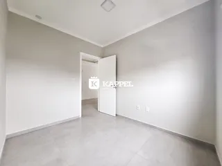 Hall de entrada com paredes brancas e piso claro.