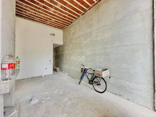Espaço interno com paredes de concreto aparente e teto inclinado.