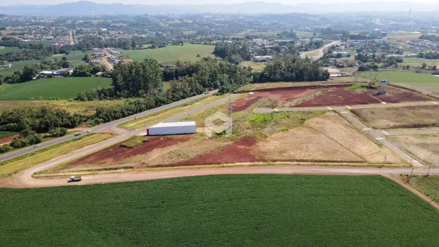 Vista aérea de campos agrícolas e vegetação ao redor de uma estrada no interior do Brasil.