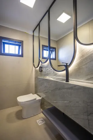 Interior de um banheiro moderno com revestimento em mármore e espelhos grandes.