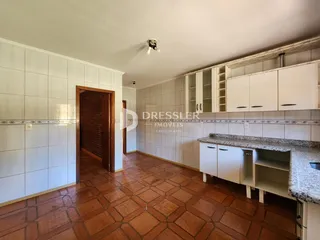 Ambiente interno de uma cozinha com piso de terracota e armários brancos.