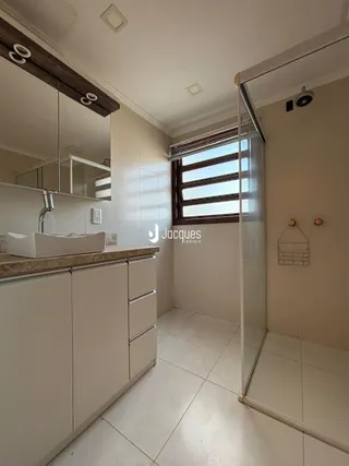 Interior de um banheiro com bancada e piso de cerâmica clara.