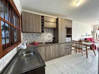 Cozinha com armários de madeira e revestimento de azulejos brancos.