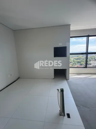 Ambiente interno de uma sala ampla com piso claro e grande janela.