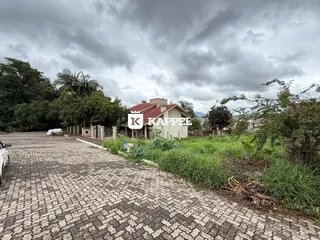 Fachada de uma residência em Lajeado, Brasil, com paisagismo e acesso por estrada de paralelepípedos.